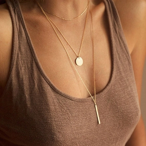 Collana multistrato in acciaio inossidabile dorato con pendenti a cerchio e barra su modella