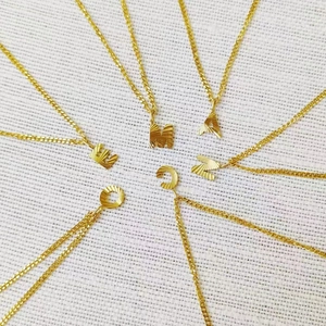 Detalle de cadena cubana de 2mm bañada en oro con colgantes de letras grabadas