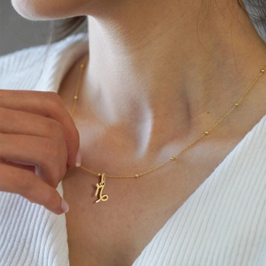 Gros plan d'un collier Capricorne plaqué or porté par un mannequin en studio