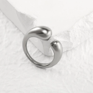 Makroaufnahme minimalistischer silberner Wassertropfen-Ring auf weißer Steinoberfläche