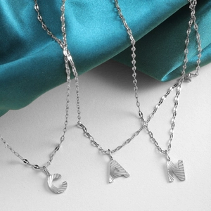 Macro view of silver alphabet pendants C, A, N with detailed radial texture and link chain