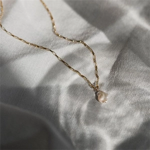 Detalle del colgante de perla barroca en un collar de cadena de clip dorado
