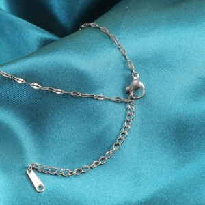 Detail of silver chain lobster clasp and extension link on blue silk background