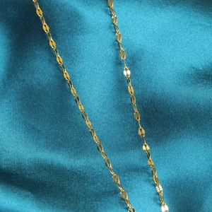 Macro-opname van een platte goudkleurige bladschakelketting op luxe blauwe satijnstof