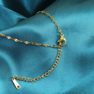 Gouden lippenketting detail met karabijnsluiting en verlengstuk op blauwe zijden stof