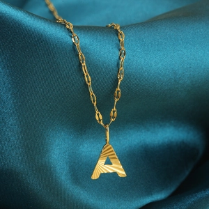 Macrodetail van de vergulde letter A-hanger met radiale textuur op blauw satijn