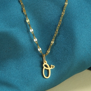 Detailopname van gouden letter O-hanger met hartje op een zijdeachtige achtergrond
