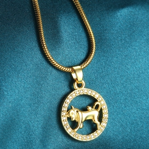 Macro detail of golden Taurus zodiac pendant with pavé crystals on silk background