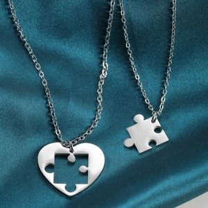 Stainless steel heart puzzle necklace set for couples on blue silk textured fabric