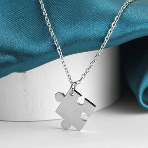 Polished stainless steel puzzle piece pendant necklace on elegant blue silk fabric