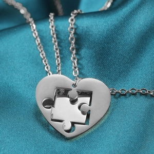 Close-up of stainless steel puzzle heart necklaces on blue silk fabric texture