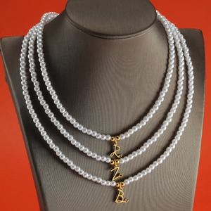 Detailed view of pearl necklace featuring gold initial pendants R Z B and heart charms