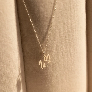 Golden stainless steel necklace featuring a cursive letter W and heart pendant design