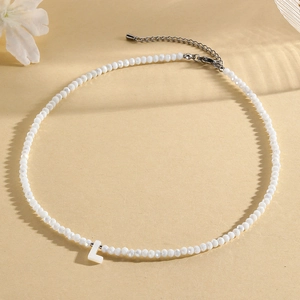 Macro shot of white faceted bead necklace with an uppercase L letter pendant detail