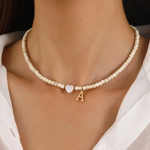 Detail of beaded necklace featuring white marble beads and a gold letter A heart pendant