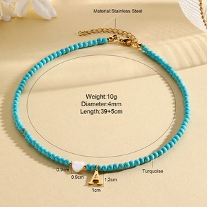 Detail of turquoise beaded necklace featuring white heart and gold letter A pendants
