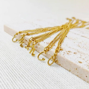 Dettaglio della collana con ciondolo a lettera dorata con piccoli accenti a cuore