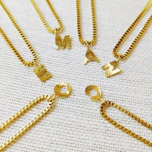 Detail of gold letter necklaces M, A, E, N, O, C with unique radial engraved textures