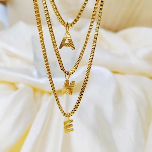 Detail of gold initial necklaces with radial texture on elegant satin background