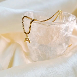 Detail of gold initial A pendant with radial engraving on a box chain necklace