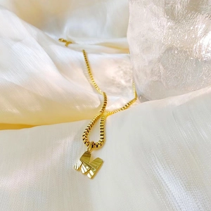 Detailed view of a gold initial M pendant with radial texture on a box chain