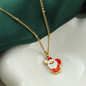 Goldene Weihnachtskette mit Weihnachtsmann-Anhänger auf grünem Satin und Keramik