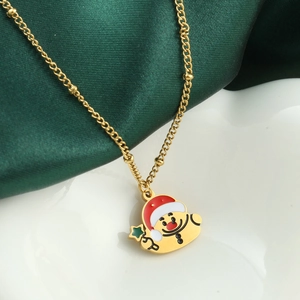 Goldene Weihnachtskette mit Cartoon-Anhänger auf dunkelgrünem Seidenhintergrund