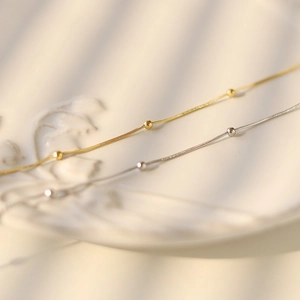 Detailed macro view of minimalist gold and silver snake chains with delicate beads