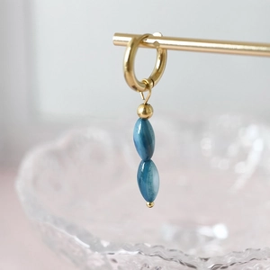 Dettaglio di orecchini a cerchio dorati con ciondoli a perle ovali effetto marmo blu