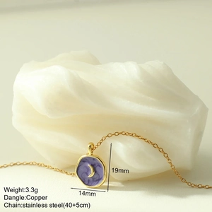 Close-up of golden moon star pendant with purple enamel on a fine stainless steel chain