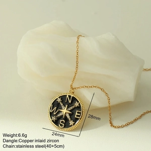 Detail of compass pendant with black enamel star and cubic zirconia on gold chain