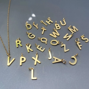 Vue macro de pendentifs alphabet en acier titane doré avec finition polie