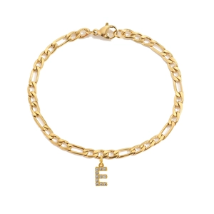 Detail van gouden Figaro kettingarmband met een fonkelende met kristallen bezette letter E-hanger