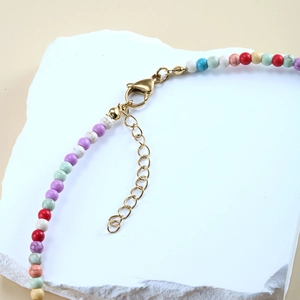 Makro-Detail einer bunten Boho-Perlenkette mit goldenem Karabinerverschluss und Kette