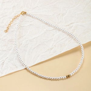 Detail of round white pearl necklace featuring gold spacer beads and adjustable lobster clasp
