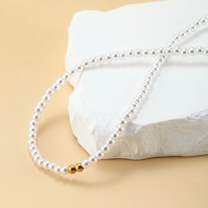 Detailed view of elegant pearl necklace with gold bead accents on a stone pedestal