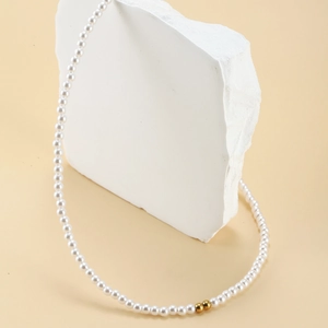 Elegant French style pearl necklace with gold beads on a minimalist white stone base