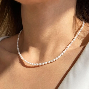 Dettaglio artistico del girocollo con perle da 3-4 mm sul collo con luce naturale