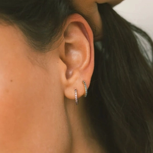 Macro shot of small gold hoop earrings with micro-pave purple and blue zircon stones