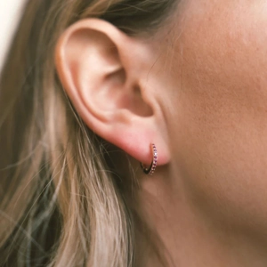 Close-up of gold hoop earrings with pink gemstones on model for a stylish look