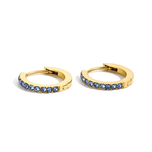 Close-up of golden stainless steel huggie earrings with round blue cubic zirconia stones