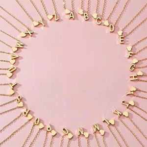 Detail of 26 golden alphabet heart charms on dainty cable chains over pink background