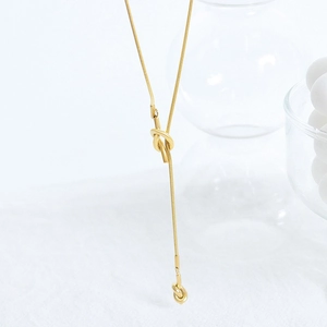 Detail of adjustable golden snake chain necklace featuring elegant knot decorations