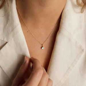 Nahaufnahme einer goldenen Halskette mit rundem Zirkonia-Anhänger an einem Model