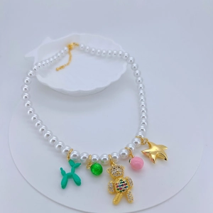 Detail of pearl necklace featuring colorful balloon dog, bear and starfish pendants