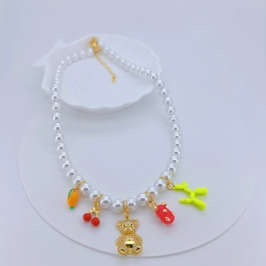 Macro detail of a pearl necklace with colorful bear, carrot, and cherry charms