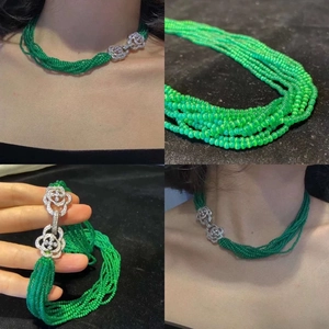 Detailed view of multi-layer emerald green beaded necklace with camellia diamond buckle