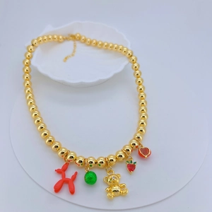 Detail of gold beaded necklace with red balloon dog, gold bear and enamel charms