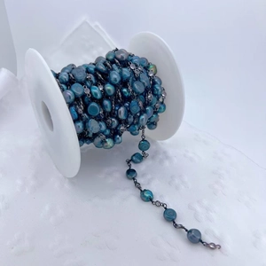 Detail of peacock green baroque pearls with cubic zirconia connectors on a spool