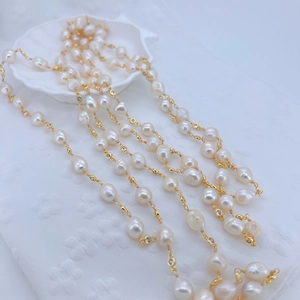Elegant baroque pearl necklace with gold chain and cubic zirconia accents on a textured cloth